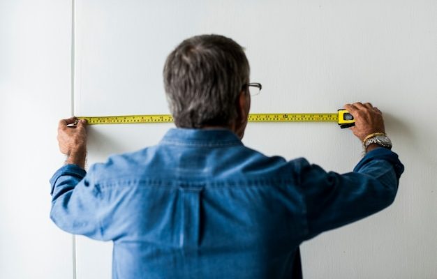Homme prenant une mesure sur un mur avec un mètre ruban avant d'installer un paravent